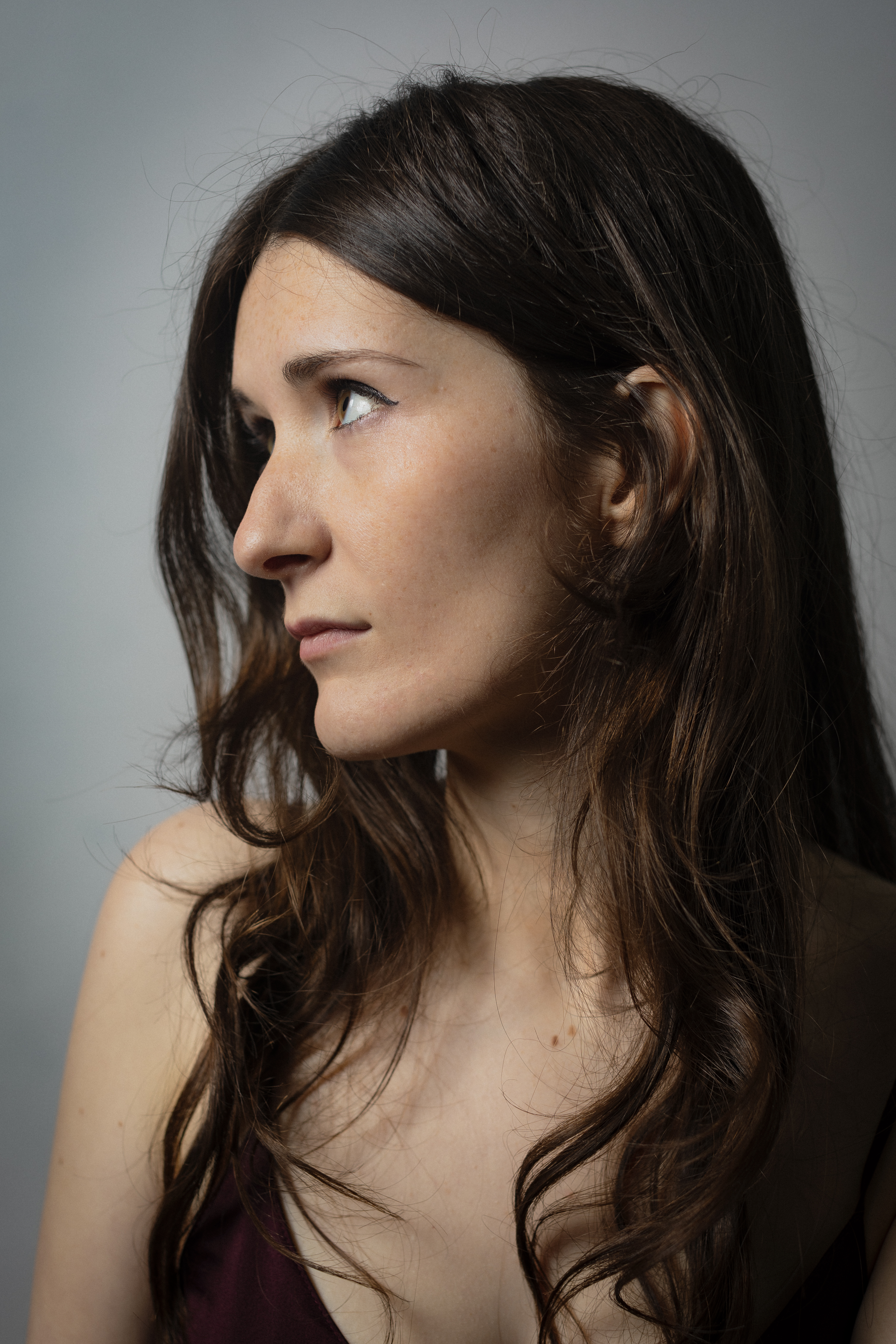 Portrait headshot of Megan, long brunette hair in wine red dress