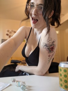 Headshot of Megan, wearing glasses with tattoos and dice for Dungeons and Dragons!